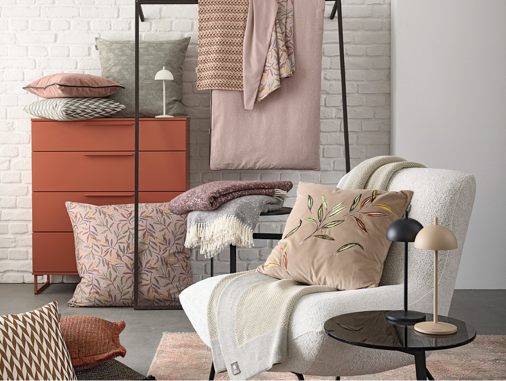 Eingerichtete Nische mit Sessel, Kommode, Tisch und Hängegestell von Musterring, die eine gemütliche Atmosphäre schaffen.