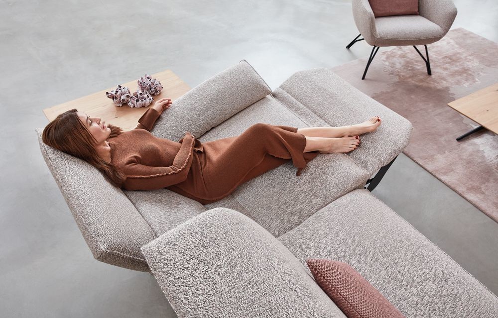 Himolla Sofa - Ultima Garnitur - Rustikca Rose Frau in relaxter Körperhaltung auf Himolla Sofa mit hochgeklappter Fußstütze und geneigter Rückenlehne