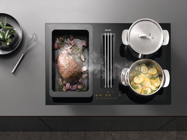 Reibungslos integriert: Miele Dunstabzugshauben für Induktionskochfelder Miele Kochfeld mit mittig integriertem Dunstabzug mit aufliegendem Lüftungsgitter