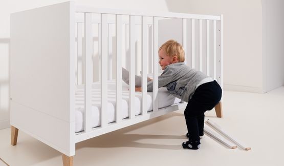 Weißes Babybett mit zwei entfernten Schlupfsprossen für einfachen Ein- und Ausstieg