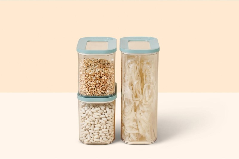 Drei transparente Mepal Vorratsdosen mit weißen Bohnen, Reis und Nudeln auf rosa Untergrund.