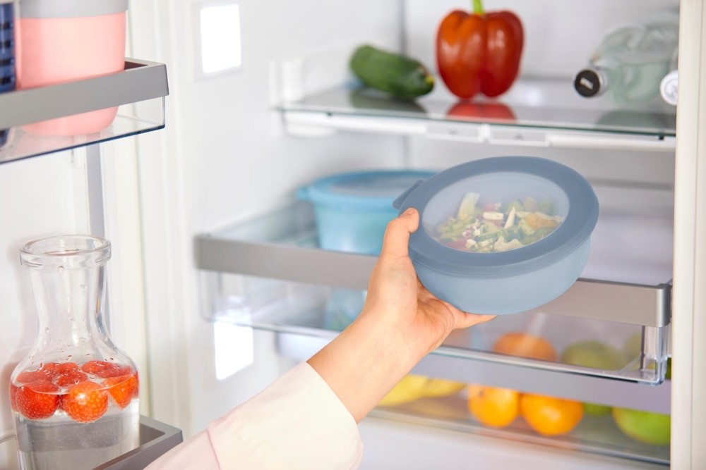 Hand holt Mepal Schüssel Cirqula mit Salat aus modernem Kühlschrank.