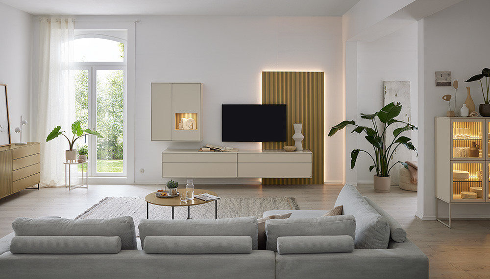 Modernes Musterring Wohnzimmer mit grauer Eckcouch, Couchtisch und Holzlamellenwand mit Fernseher.