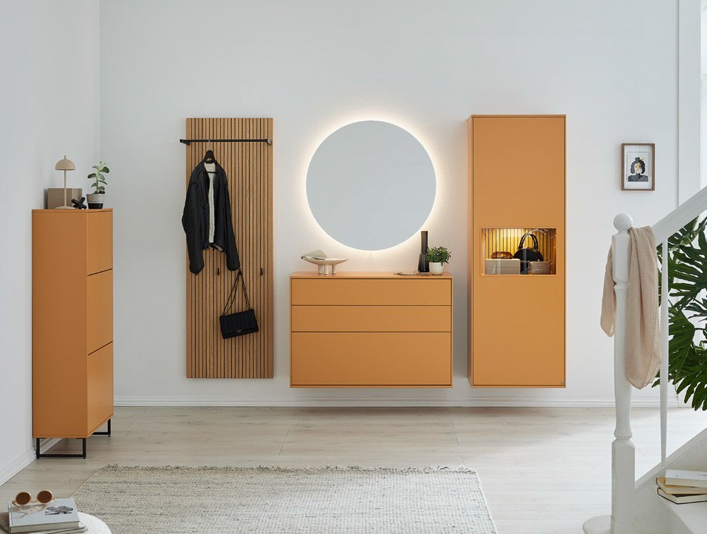 Minimalistischer Flur mit orangefarbenen Schränken von Musterring, Holzlamellenwand, Spiegel und Treppe.