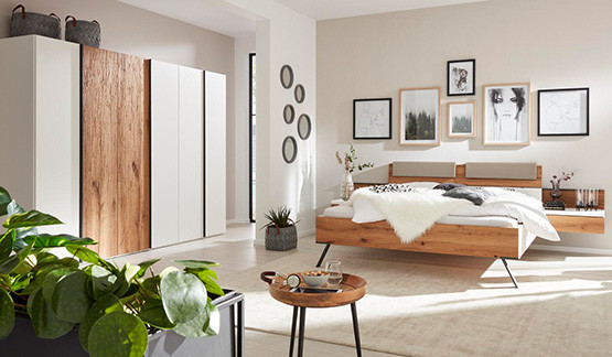 Interliving Schlafzimmermöbel Interliving Schlafzimmermöbel mit Kleiderschrank, Bett mit integrierten Nachtkonsolen und hellem Teppich