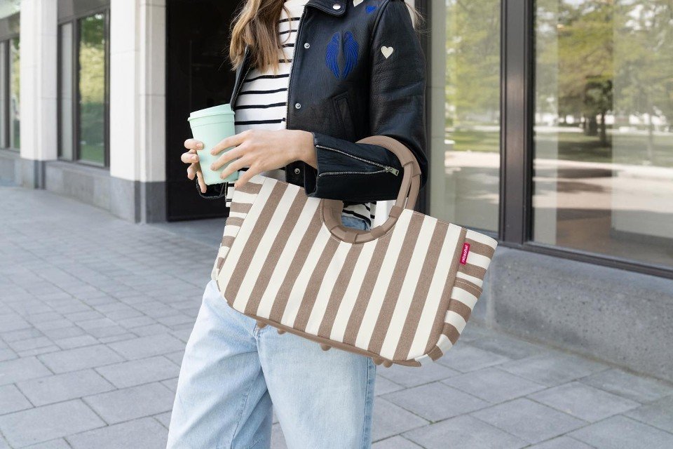 Coffeefarbener Reisenthel Loopshopper in Summerstripes-Optik am Arm einer Person