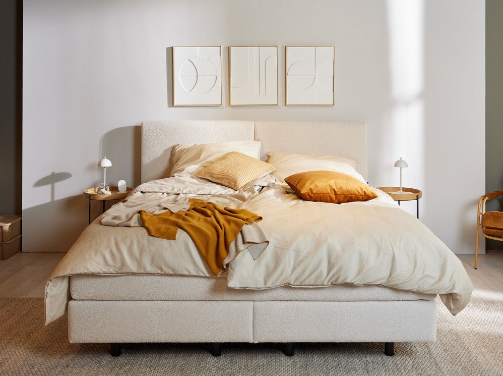 Musterring Schlafzimmer mit großem Bett, hellem Interieur und abstrakten Wandbildern.