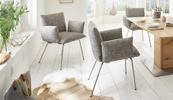 Drei graue Polsterstühle mit Metall-Beinen der Marke Venjakob neben einem Esstisch aus Massivholz