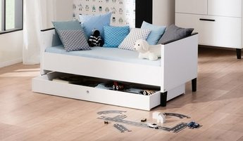 Weißes Juniorbett der Marke PAIDI mit rollbarem Bettkasten, Kuscheltieren und Zierkissen