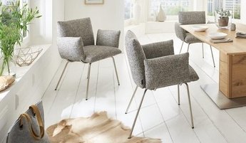 Drei graue Polsterstühle mit Metall-Beinen der Marke Venjakob neben einem Esstisch aus Massivholz