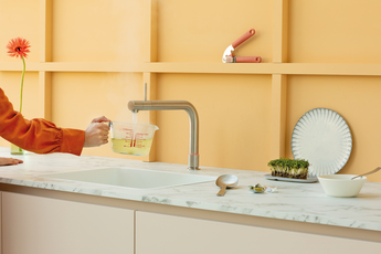 Frau bereitet Brühe mit Hilfe des Quooker Kochend-Wasserhahns zu