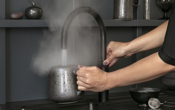 Frau gibt kochendes Wasser aus dem Quooker Fusion Round Black in eine Teekanne